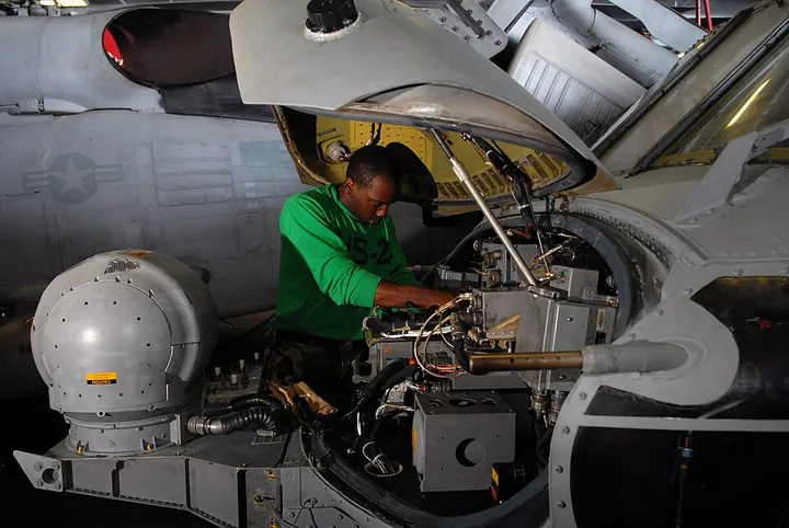 A technician maintains a helicopter avionics system during a scheduled inspection.