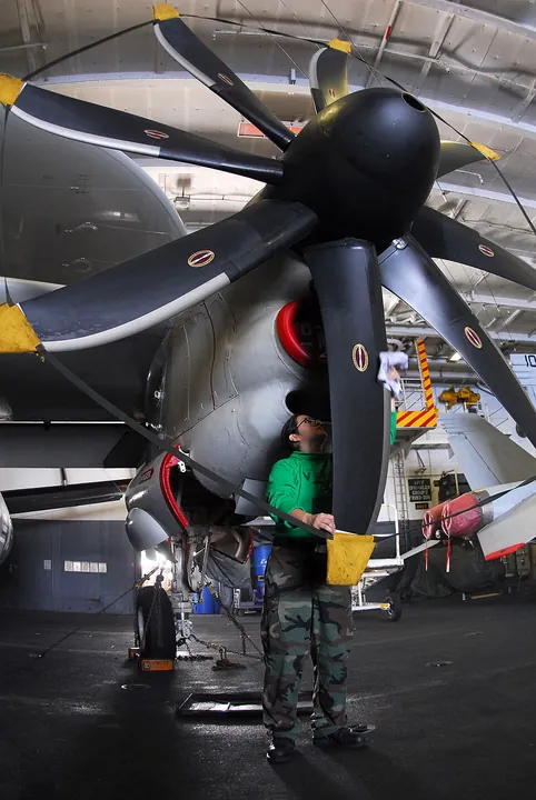 A technician cleans a propeller in a hangar.