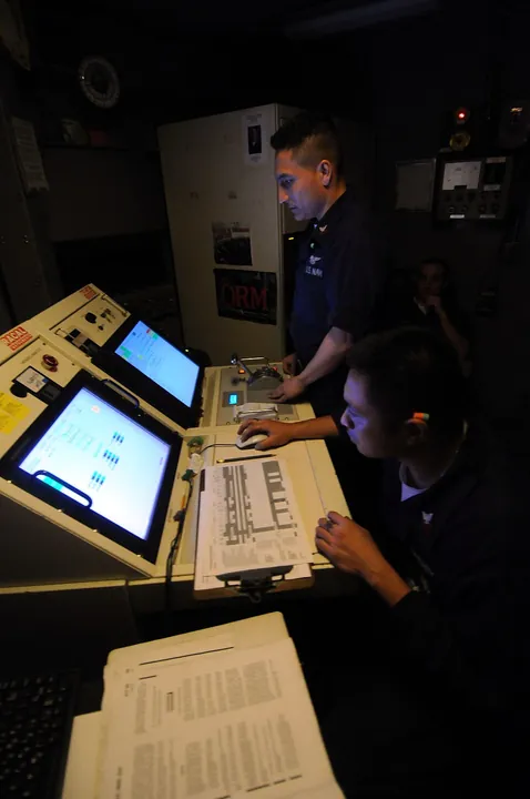 Technicians operate a control panel during an engine test.