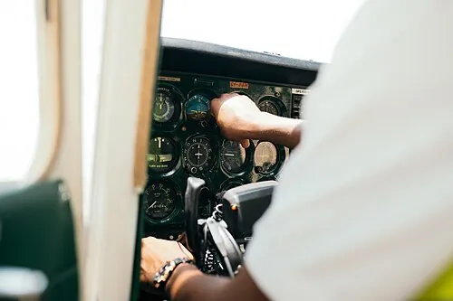 A student pilot's hand reaches toward instruments in a light-aircraft cockpit.