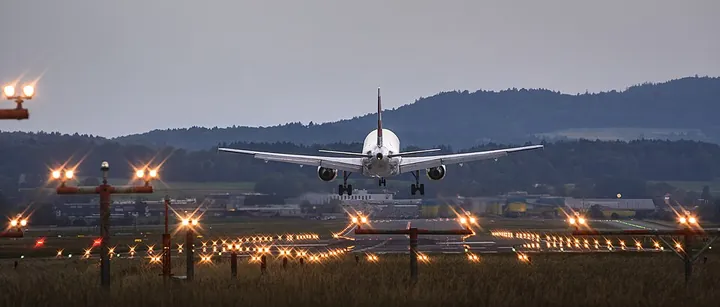 An aircraft approaching Zurich Airport above an array of airfield lights