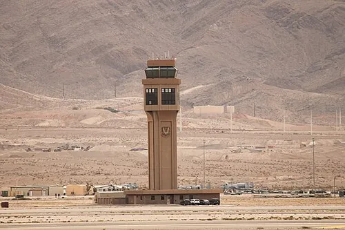 Air traffic control tower at Nellis Air Force Base against desert mountains.